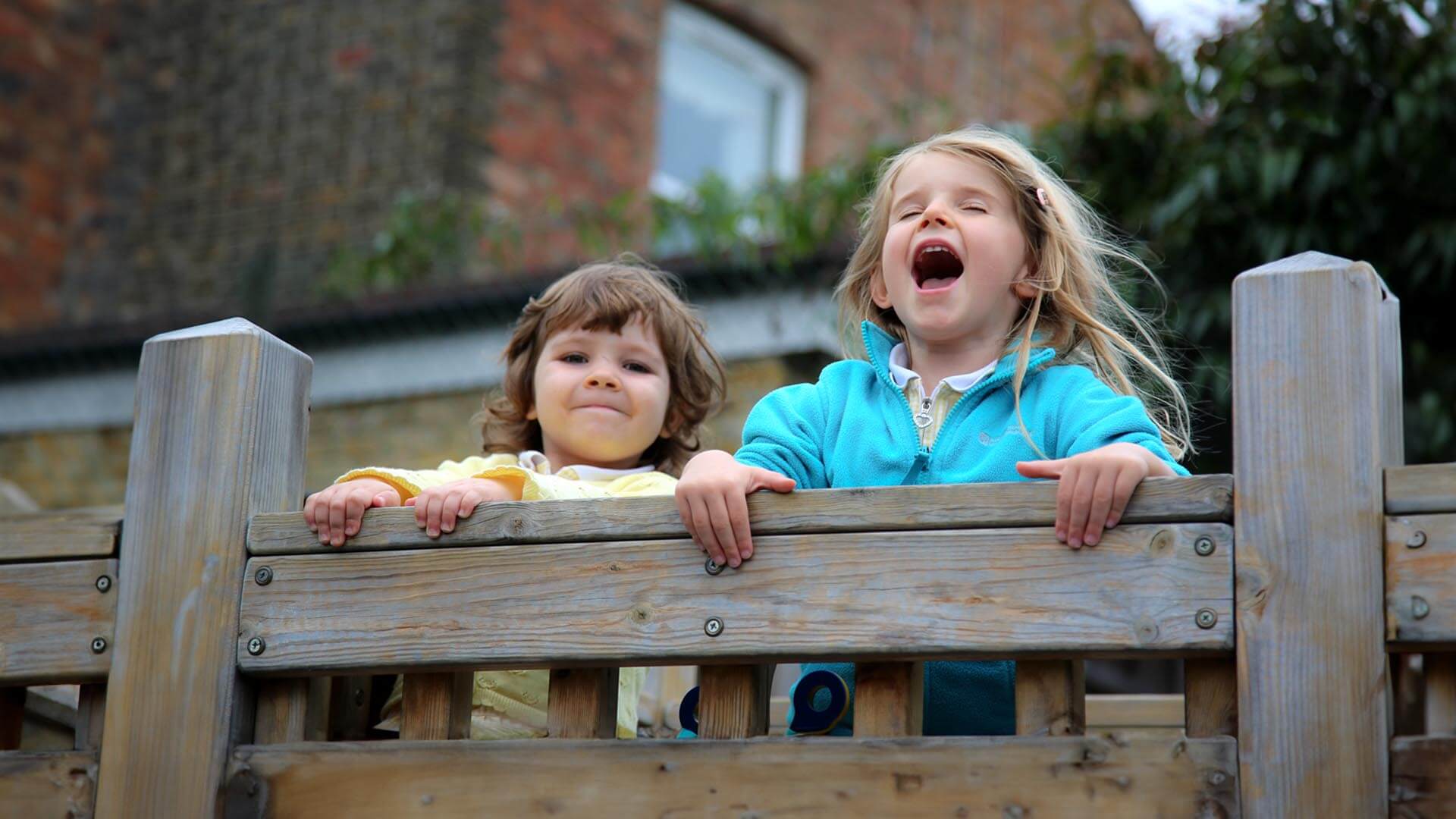 children enjoying outdoor play on a wooden structure at Watford Nursery