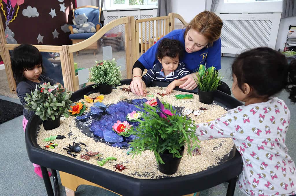 A group of young children at The Little Learners Montessori engaging in sensory play with a staff member